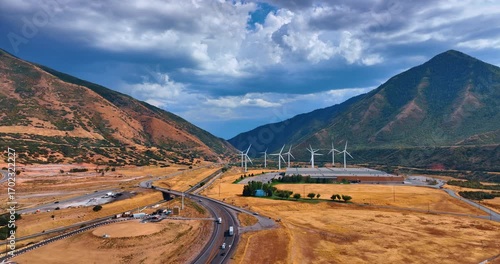 Footage over the deserted land with wind turbines rotating in the wind. Dramatic cloudscape over the rocks in Spanish Fork, Utah County, Utah, United States.