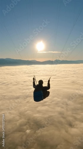 Peaceful Paragliding Flight High above Foggy Clouds at Golden Sunrise, Vertical View