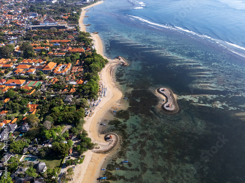 Sanur beach, Bali, Indonesia, September 01, 2025: Aerial view of pantai karang  with sandy coastline, resorts, boats, and small stone jetties surrounded by turquoise sea and coral reefs.
