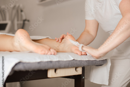 masseuse prepares the skin of the client's feet before foot massage