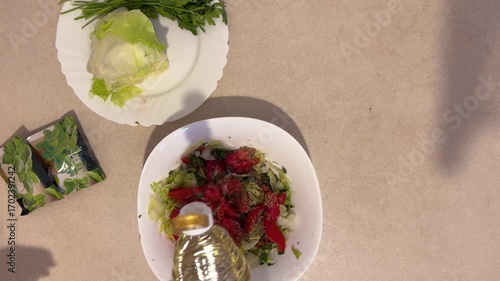 Adding oil and salt to a mixed chopped salad on a plate, top view