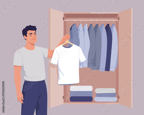 Man holding white t-shirt in front of wardrobe with folded clothes and hanging shirts
