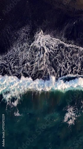 Wallpaper Mural Aerial looking down at waves on a black sand beach in Bali Indonesia. Vertical Video. Torontodigital.ca