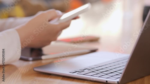 Person is using a laptop and a cell phone. The laptop is open and the cell phone is in the person's hand