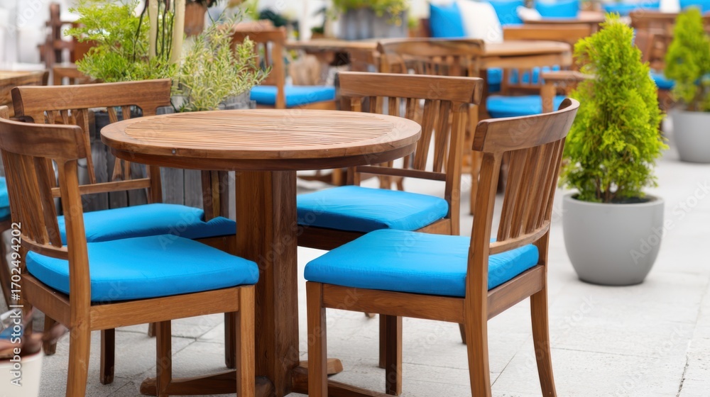 Fototapeta premium Elegant outdoor dining area with wooden furniture and vibrant blue cushions on a sunny day