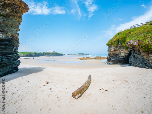 Playa des Catedrales in Galicia Spain sandstone rocks tidal pools sky cliffs wide shore under bright light clear blue sky peaceful calm natural wonder