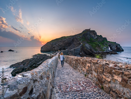 Ancient stone bridge leading to Gaztelugatxe islet at sunset Basque Country Spain symbol of journey solitude spirituality dramatic seascape inspiration