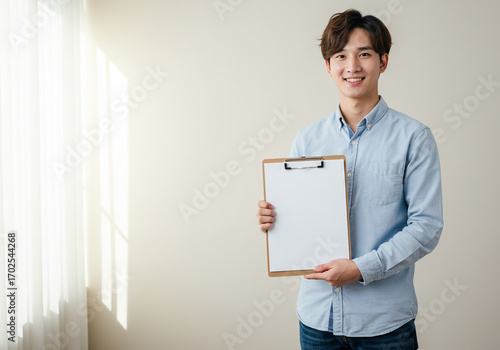Confident young man proudly presents blank clipboard for your important message or data