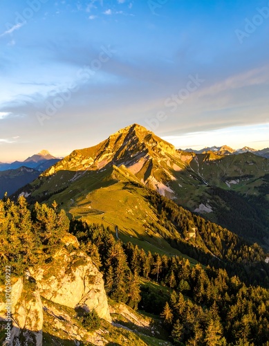 Mountain peak bathed in golden sunrise light, with valleys and forests below