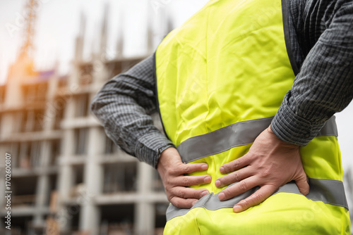 A construction worker, suffering from back pain. The scene conveys the physical toll of manual labor and workplace safety concerns.