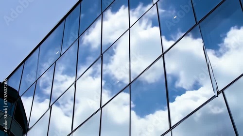 Modern glass facade reflecting a blue sky and clouds