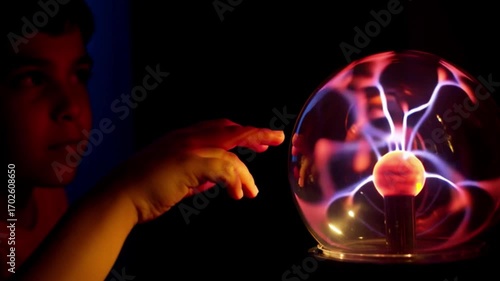 4k Boy playing with plasma ball electric energy close up view, child hand touching glowing lightning inside glass sphere, interactive science experiment, physics electricity concept, educational techn
