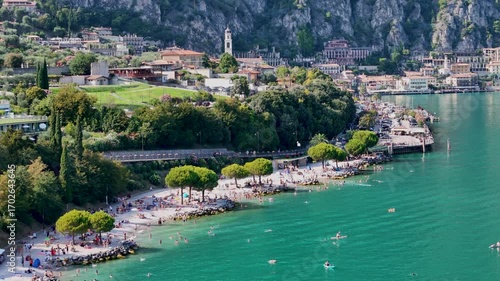 Limone sul Garda beach with people at a beach swimming and sunbathing. Aerial 4K video footage of panoramic lake Garda. Lombardy drone landscape