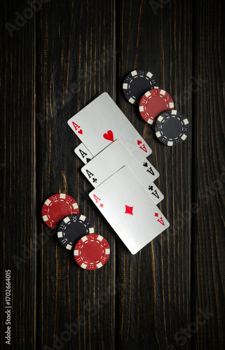Obraz na płótnie Four aces are laid out next to red and black poker chips on a dark wooden table