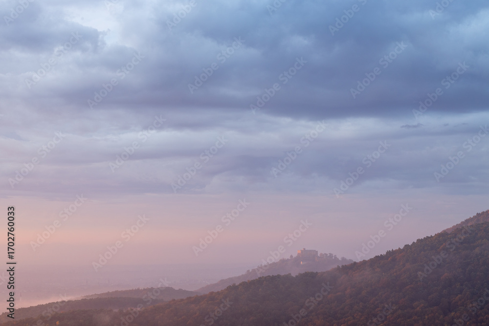 Obraz premium Hambacher Schloss im herbstlichen Sonnenaufgang mit Nebel und Wolken über dem Pfälzerwald