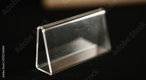 Metal nameplate displayed against sleek dark surface, showcasing its minimalist design. Metal nameplate crafted from polished metal and transparent plastic, perfect for conferences, office desks,