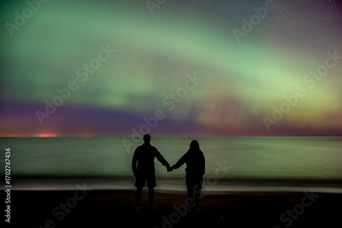 silhouette of man and woman at night looking at northern lights