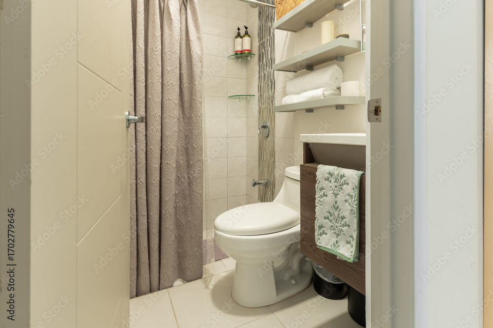 Obraz premium Modern small bathroom with floating shelves and gray shower curtain