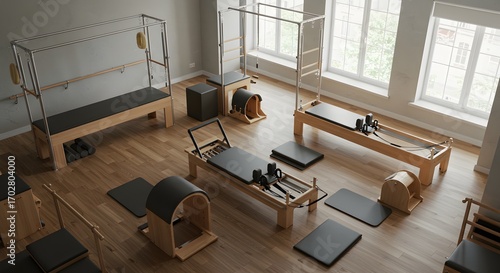 Aerial view of pilates studio with reformers and cadillacs arranged on a wooden floor near windows