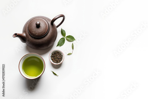 Asian tea set - iron teapot and ceramic cups with green tea and leaves. Traditional tea composition on white background, copy space.