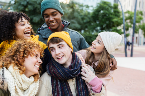 Fototapete Young group of multiracial teenage people in warm clothes having fun outside