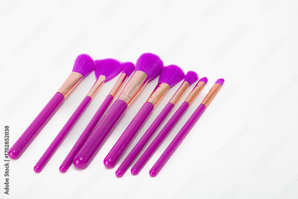 Naklejka premium A set of purple makeup brushes. The brushes are purple and have a gold trim. They are arranged in a row on a white background