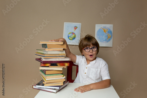 Boy Excited by a Tower of Books, a boy sits in a mountain from books