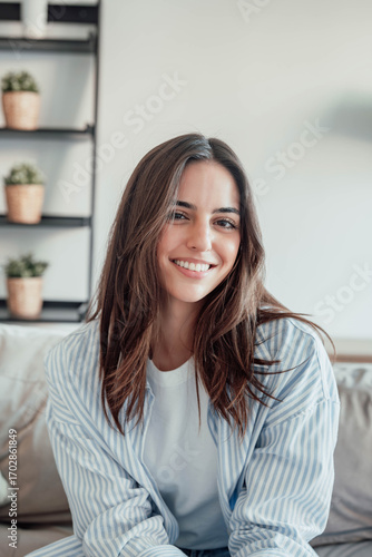 Free Download Young attractive cheerful lady sitting on sofa, relaxing looking at the camera at home. Beautiful brunette woman on her 30s chatting on video call online - GFXLoad