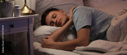 Handsome young happy man sleeping on bed in evening at home