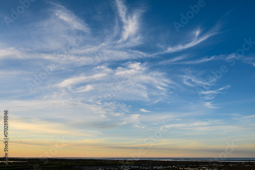 Sunset sky background over the coast of Hudson Bay, blue sky with hints of yellow and orange, and white wispy clouds
