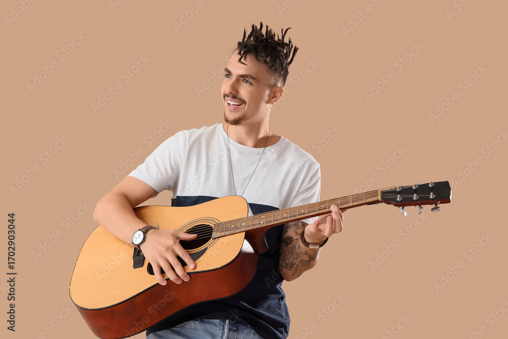 Naklejka premium Young man with dreadlocks playing guitar on beige background