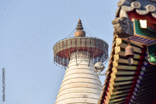 Traditional Pagoda with Ornate Roof and Bell Against Clear Sky