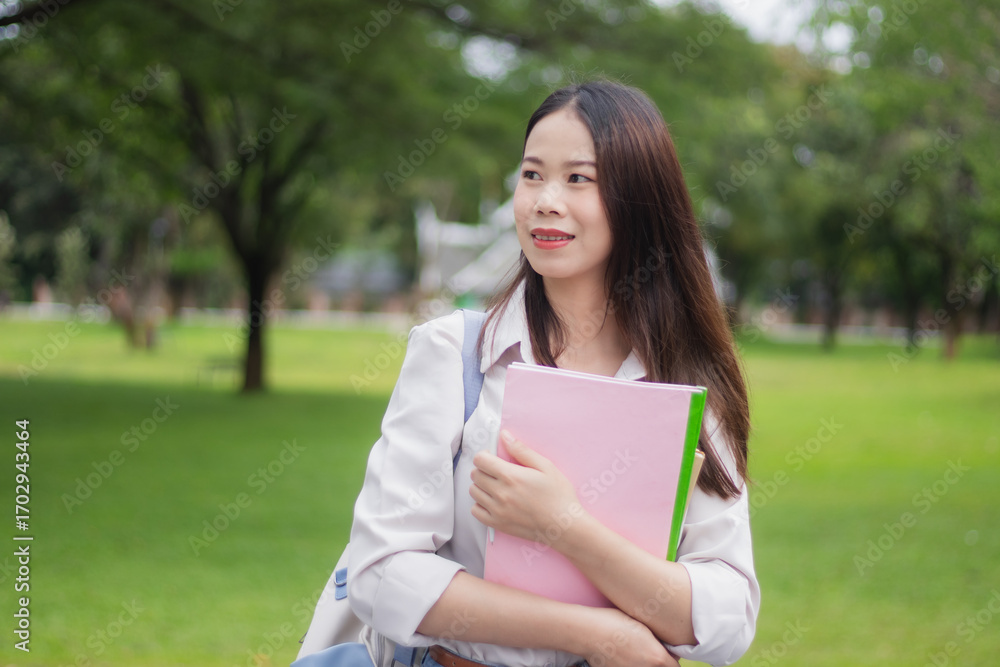 Obraz premium A female student smiles proudly in the university, studying with books and records of education, achievements and desires.