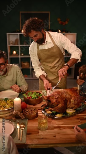 Family enjoying thanksgiving dinner, father carving turkey