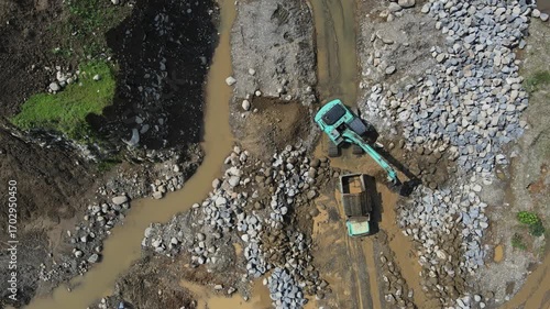 Excavator and dump truck working in rock and sand quarry, Construction and mining site view from above.