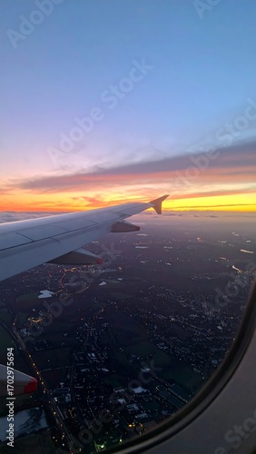 Airplane wing at sunset over city