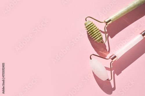 Papier peint Jade and rose quartz facial rollers on pink background for skincare and beauty routine