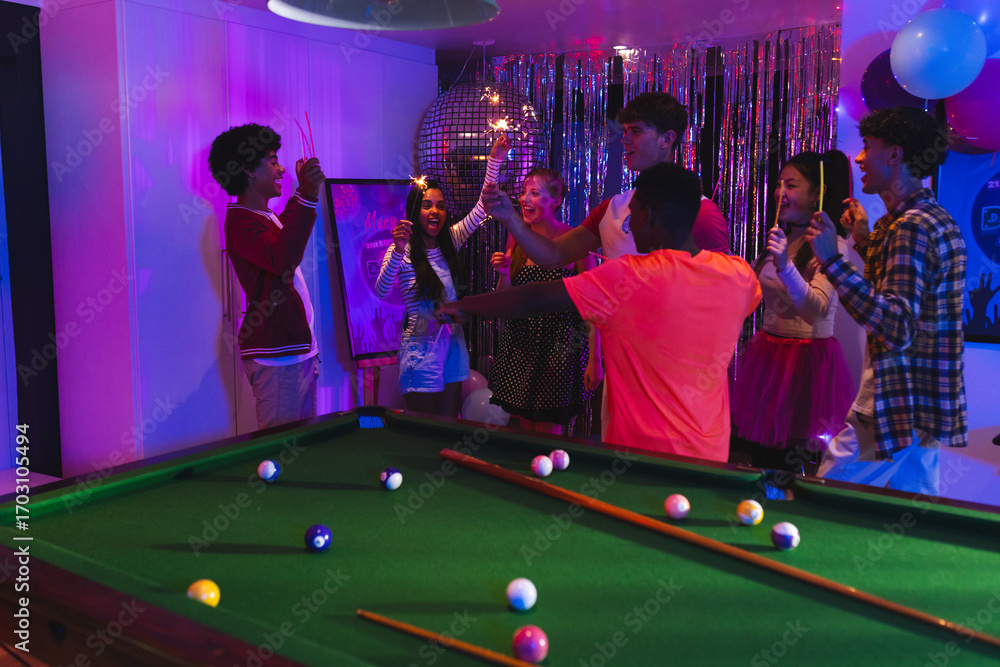 Naklejka premium Teenagers celebrating around pool table with colorful lights and festive decorations
