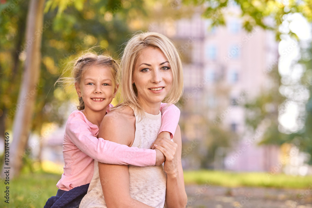 Fototapeta premium Happy caucasian mother and daughter outdoors in park smiling together.