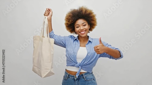 Eco-Friendly Elegance: A stylish person proudly displays a reusable shopping bag while giving a cheerful thumbs-up. Captured in a captivating portrait.