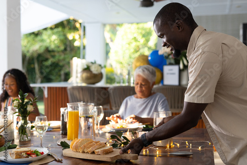 Serving fresh bread at family gathering, smiling and enjoying outdoor meal together
