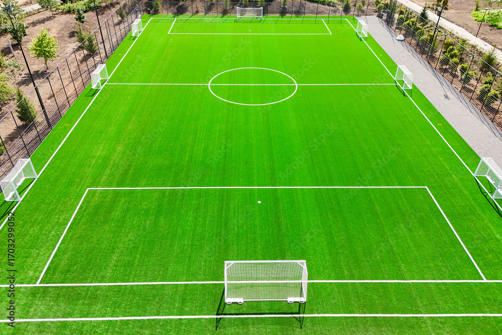 Fototapeta premium A soccer field with a white goal and white lines. The field is green and well maintained. Concept of sportsmanship and teamwork