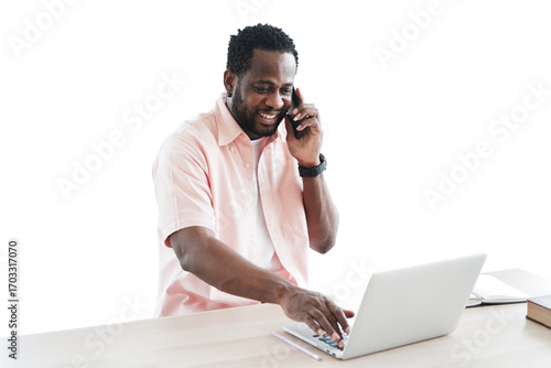 African American businessman using and talking smartphone for online working with laptop on desk