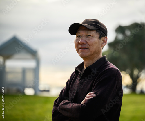 Man smiling and looking ahead. Blurred public park background.
