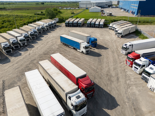 Aerial view of a large truck parking lot at a logistics hub, with multiple commercial semi trucks parked in organized rows