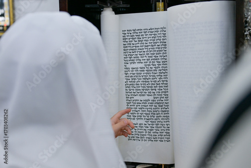 A bar mitzvah boy reading from the Torah scroll in a synagogue.
