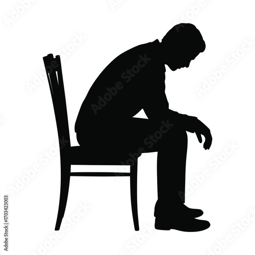 Silhouette of a man sitting alone on a chair with his head bowed in contemplation or sadness