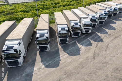 Aerial view of a large truck parking lot at a logistics hub, with multiple commercial semi trucks parked in organized rows