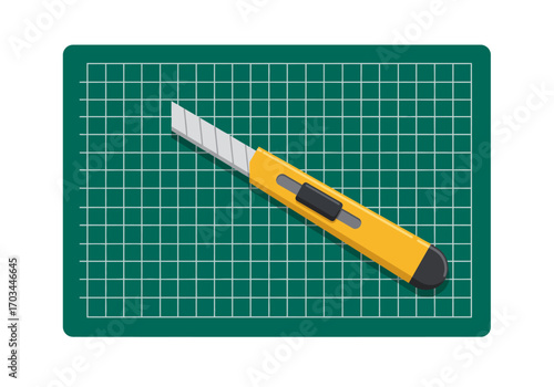 A box cutter sits atop a gridmarked green cutting mat