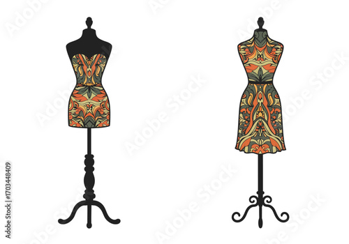 Two dressmakers dummies display patterned dresses on ornate black stands against a white backdrop